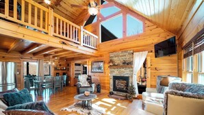 A spacious log cabin interior with a dining area, fireplace, and a balcony. - Serenity Retreat - Mountain Escape- Grandview Peaks (Nebo)