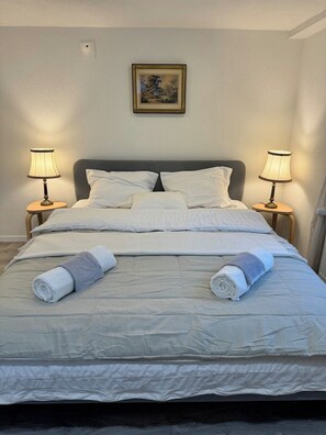 A neatly made bed with white linens, two bedside lamps, and a framed picture on the wall. - Bijou Lungern 2 (Lungern)
