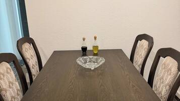 Une table à manger avec six chaises, une tête de cerf décorative fixée au mur et deux bouteilles d’huile d’olive.