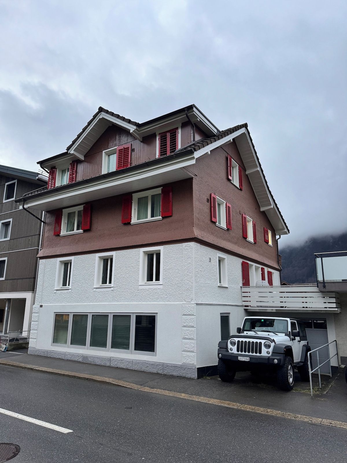 Un immeuble à plusieurs étages avec un garage et un véhicule blanc garé devant.
