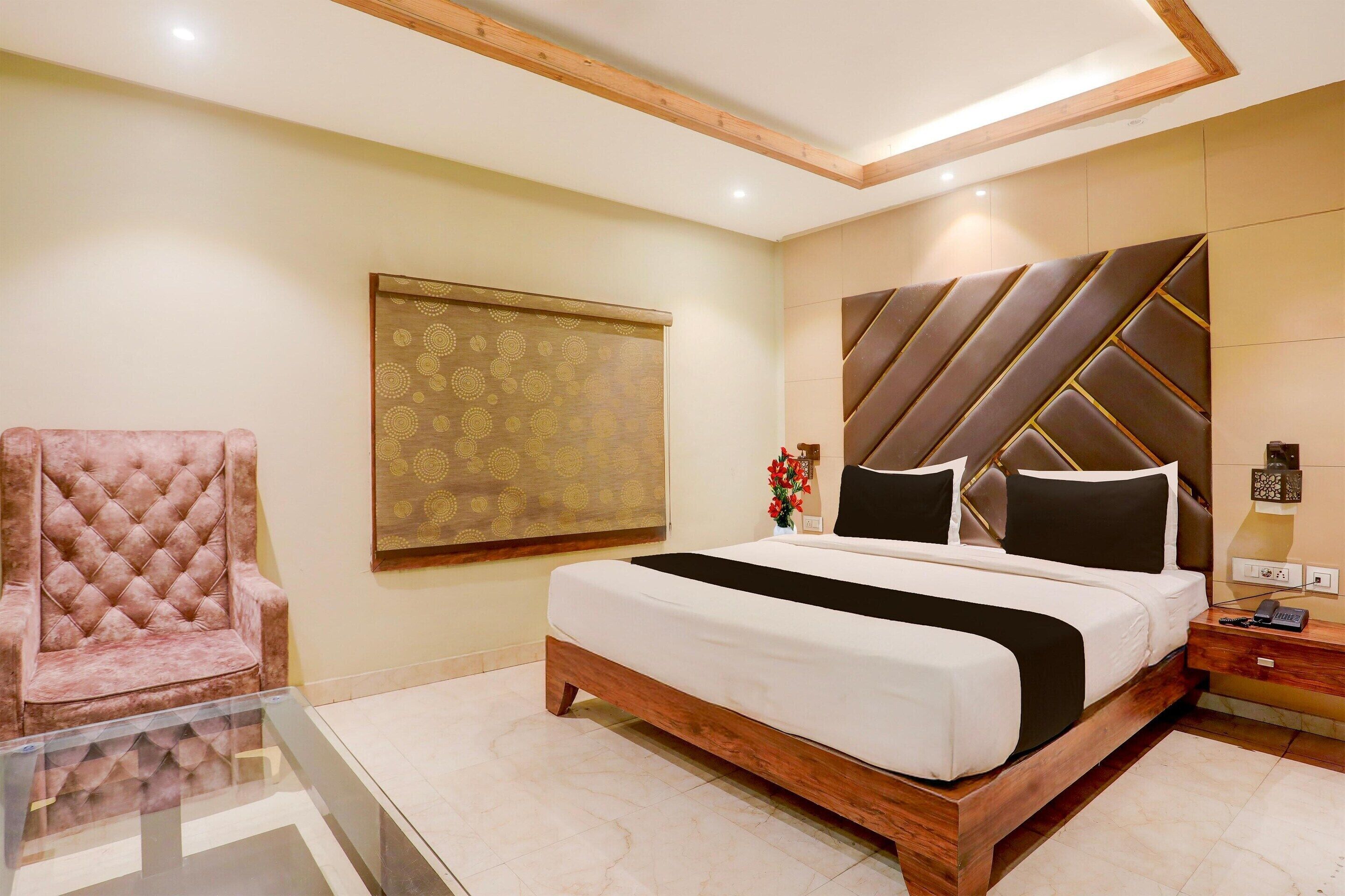 A bedroom with a bed, a chair, a nightstand, and a wall with a geometric pattern.