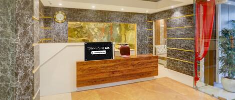 A reception desk with a sign reading 'TOWNHOUSEOAK,' a clock, and a modern interior design with marble walls and a wooden reception counter.