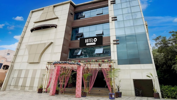 A modern hotel building with a prominent 'HOTEL O' sign, large windows, and a decorative entrance with plants.
