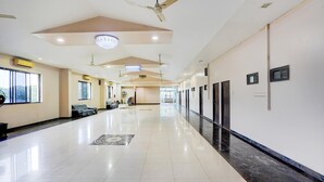 A long, well-lit corridor with ceiling fans, recessed lighting, and a marble floor.