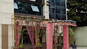 A building entrance with a decorative archway, potted plants, and a sign indicating it's company-serviced.