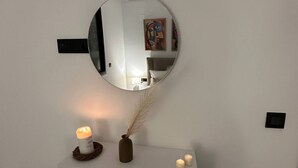 A round mirror on a white wall, reflecting a room with a bed, a lamp, and a painting. - Absolute Comfort in a Luxury Residence, Soukra (Tunis)