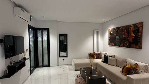A modern living room with a flat-screen TV, a sofa, a coffee table with candles, and a large abstract painting. - Absolute Comfort in a Luxury Residence, Soukra (Tunis)