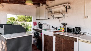 A rustic kitchen with a wooden counter, a white refrigerator, and a hanging light fixture.