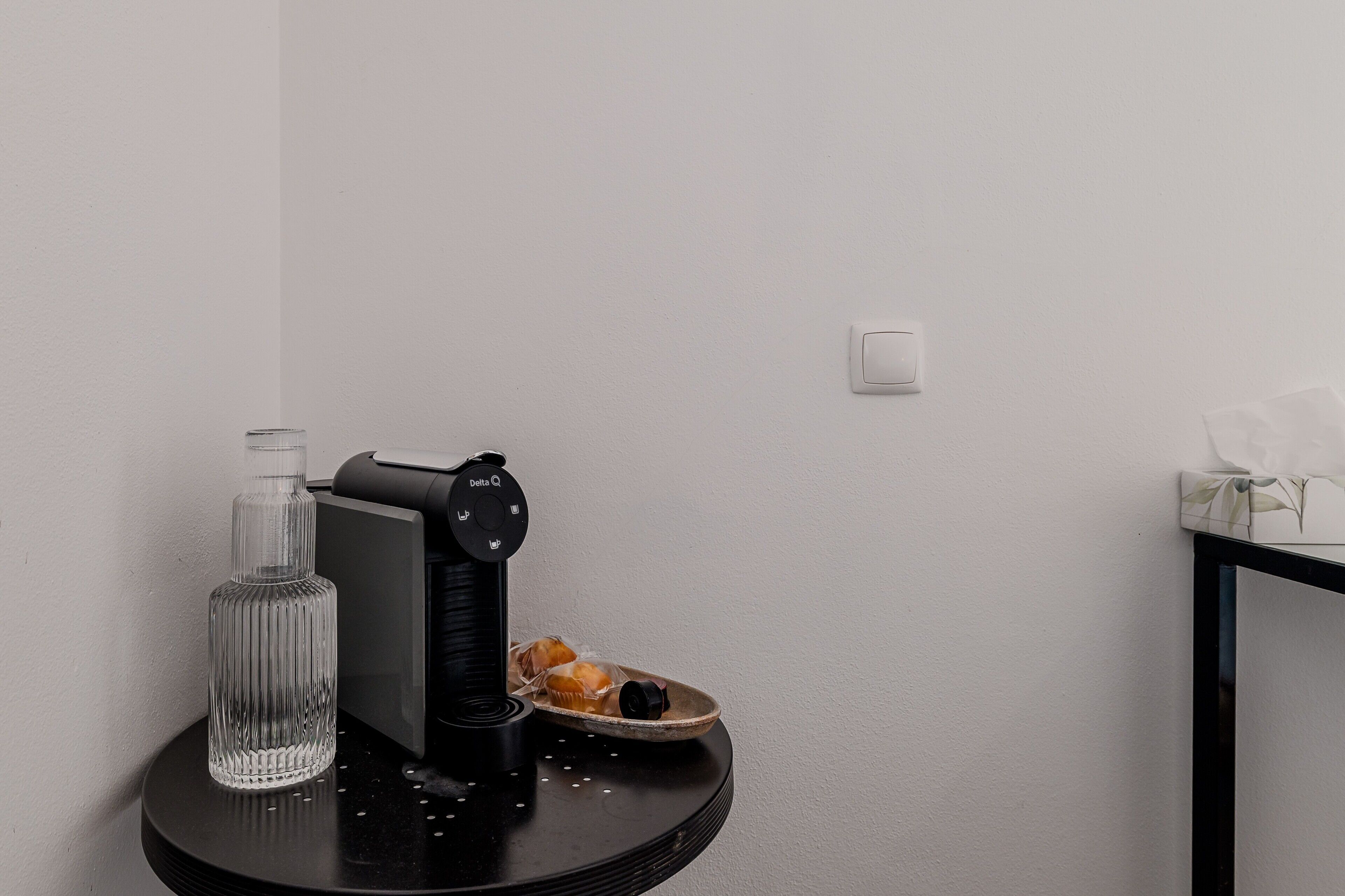 A small table with a black object, a clear bottle, and a plate with food.