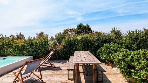 A wooden deck with a pool, a table, and chairs.