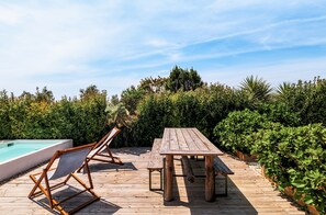 Una terraza de madera con piscina, mesa y sillas.