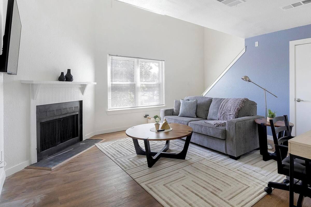 A living room with a fireplace, a sofa, a coffee table, and a desk with a chair.