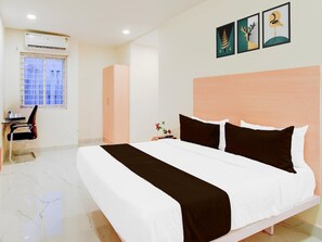 Habitación de hotel con cama, escritorio, silla, armario y obras de arte en la pared.