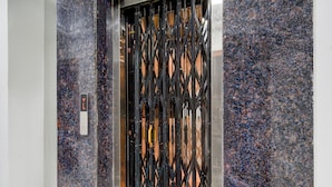 An elevator with a black metal gate and a marble wall. - Super Townhouse JP Nagar Miyapur (Hyderabad)