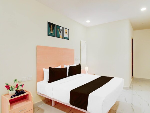Una habitación de hotel con cama, mesita de noche, lámpara y una obra de arte en la pared.