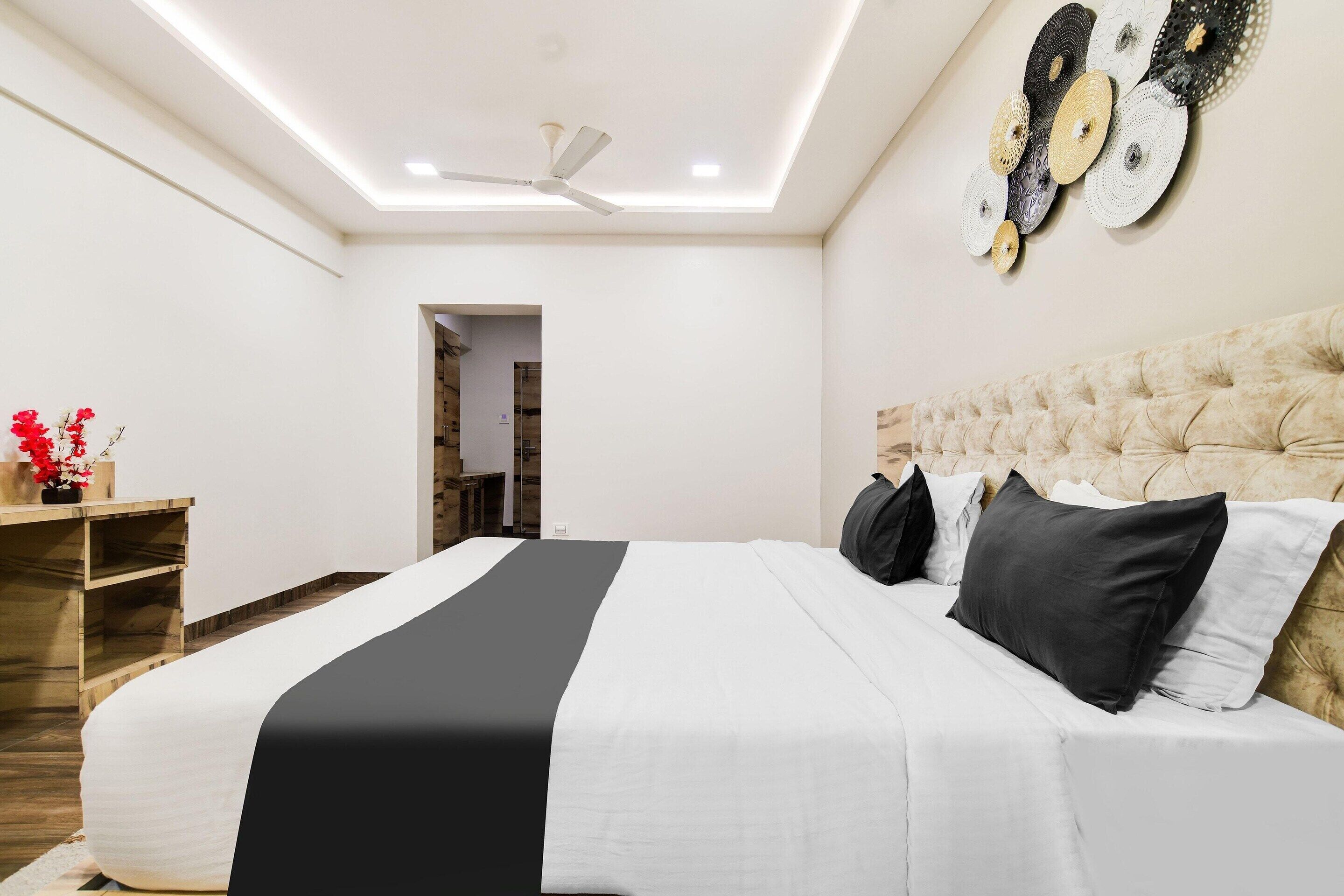 A modern bedroom with a large bed, a ceiling fan, and a wall art piece.
