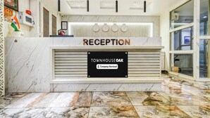 Een receptiebalie met een bord waarop 'RECEPTION' en 'TOWNHOUSE OAK Company-Serviced' staat.