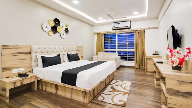 Een moderne hotelkamer met een groot bed, een houten hoofdbord, nachtkastjes, een bureau en een raam met gordijnen.