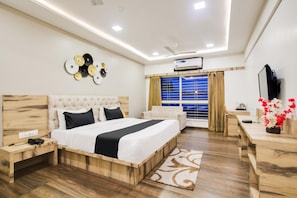 A modern hotel room with a large bed, wooden headboard, bedside tables, a desk, and a window with curtains. - Townhouse Oak PTC Indore Junction (Indore)