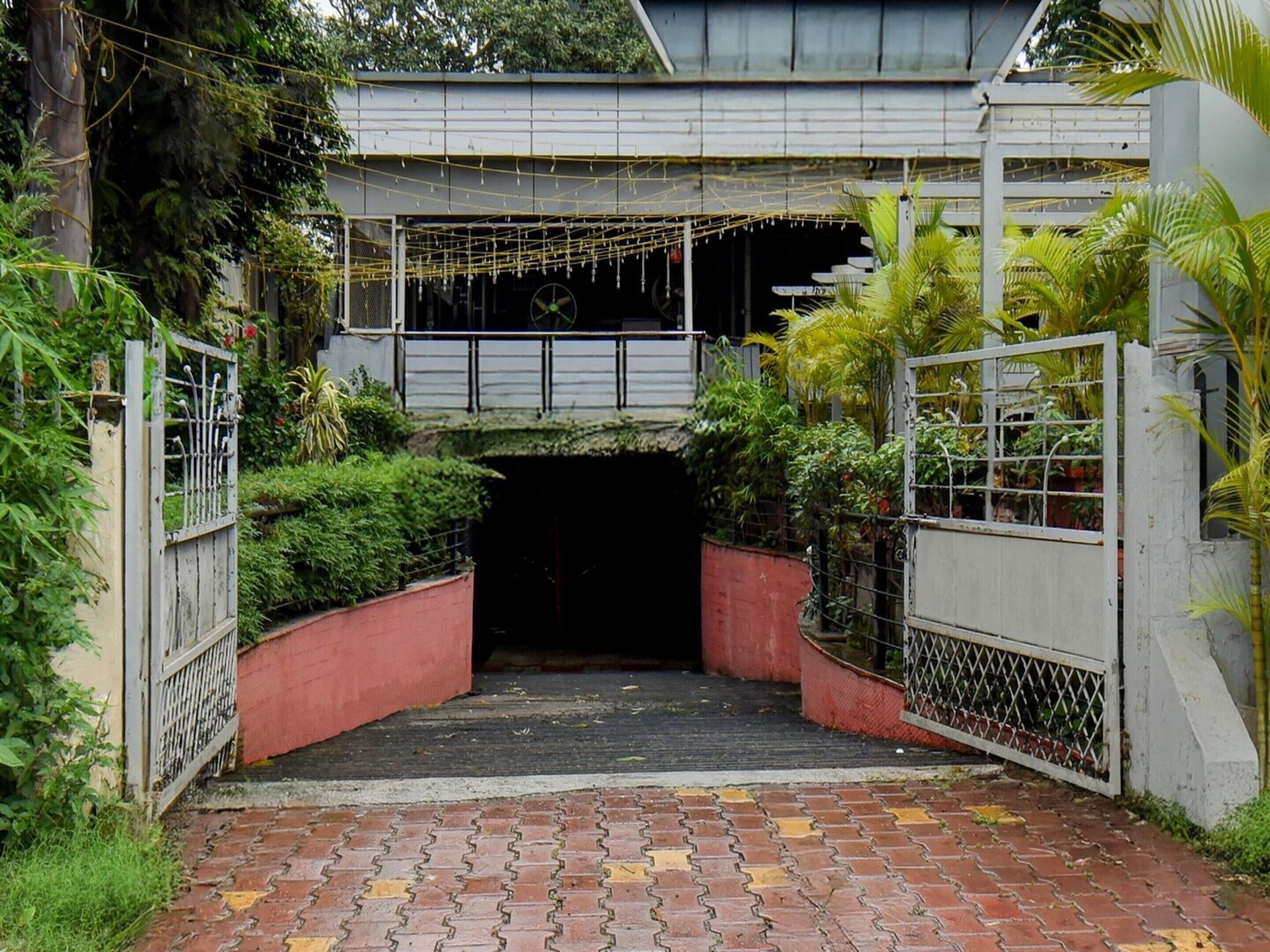 Uma entrada com portão e um caminho de tijolos que leva a uma área coberta.