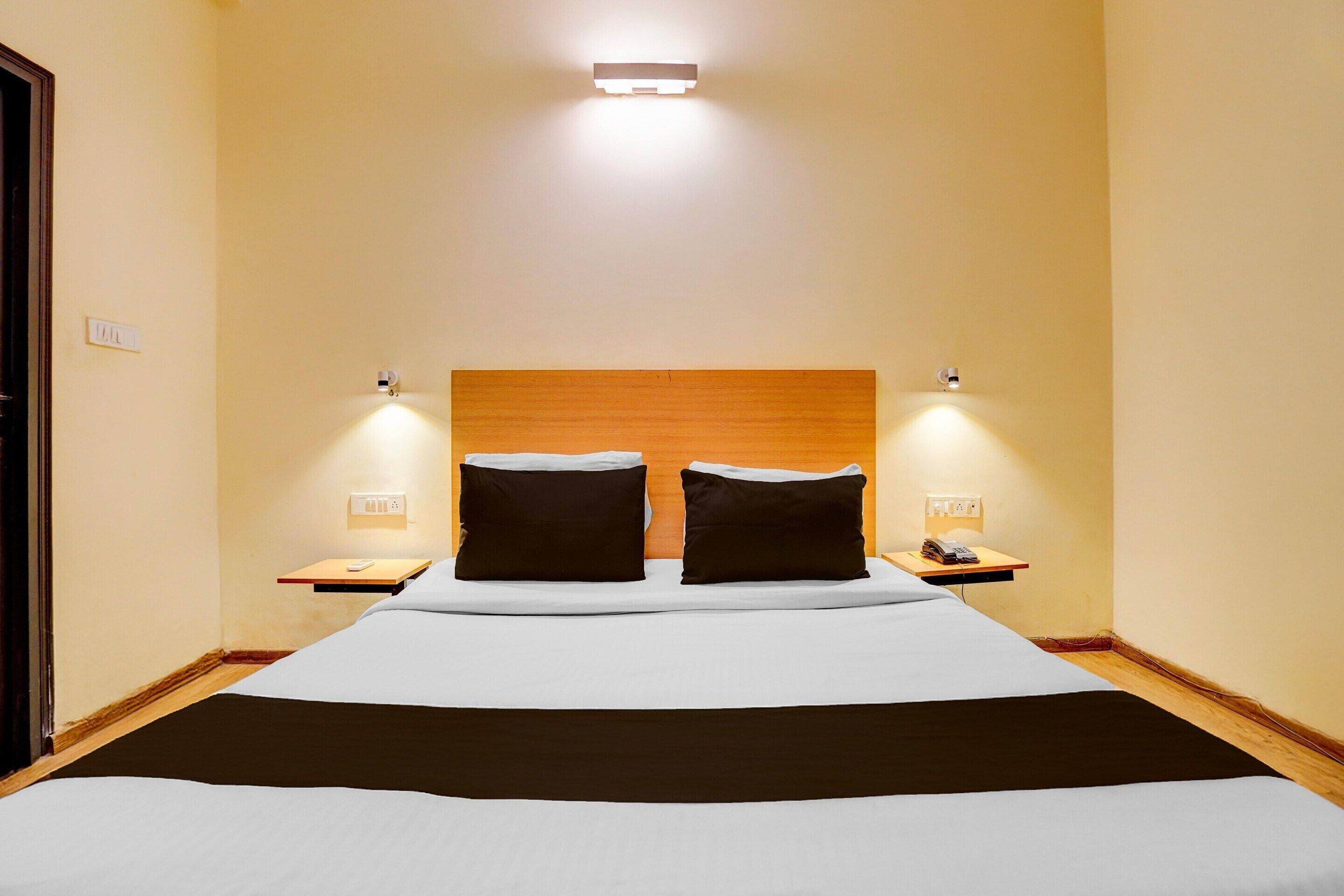 Ein Hotelzimmer mit einem großen Bett, zwei Nachttischen, einem Holzkopfschild und Wandleuchten.