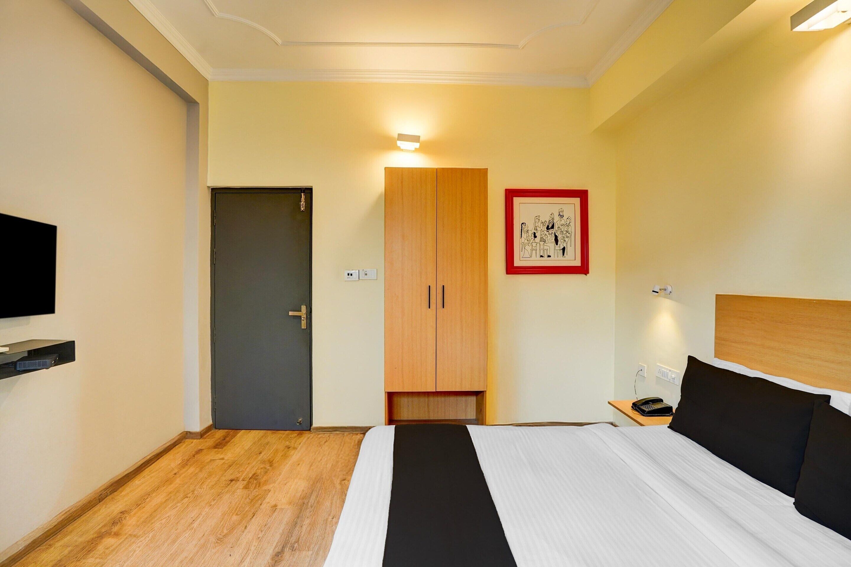 A hotel room with a bed, a wardrobe, a television, and a framed picture on the wall.