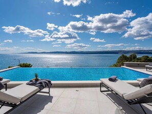 Una piscina con sillas de descanso y vistas al mar.