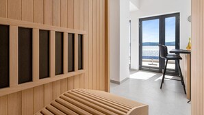 A modern interior with a wooden panel wall, a bench, a table with chairs, and a view of the sea through large windows. - Estate With Jacuzzi, Gym (Omis)