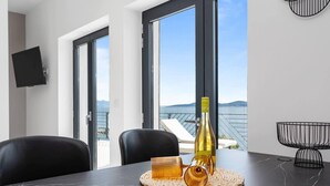 A modern room with a dining table, a bottle of wine, and a woven placemat. - Estate With Jacuzzi, Gym (Omis)