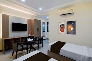 A modern hotel room with a flat-screen TV, a dining table with chairs, a bed, and a wall-mounted air conditioner. - Deluxekhajaguda Premium Suites (Hyderabad)