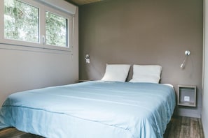 A bedroom with a bed, two bedside tables, a window, and a wall-mounted light fixture. - Villa (Malansac)