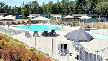A swimming pool area with lounge chairs and umbrellas, surrounded by a fence.