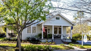 A white house with a porch, a flag, and a sign that reads 'BlueHeron.'
