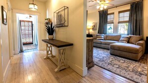A hallway with a wooden bench, a potted plant, and a wall-mounted artwork.