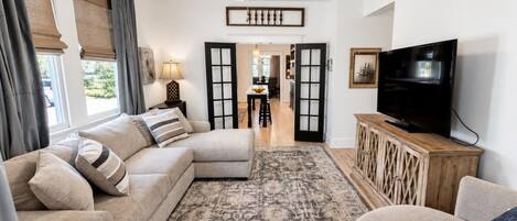 A living room with a sectional sofa, a television, and a patterned rug.