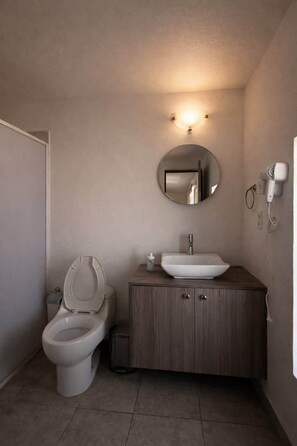 Ein Badezimmer mit Toilette, Waschbecken, Spiegel und Fön.