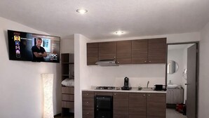 A modern hotel room with a bed, a TV, a kitchenette, and a bathroom. - Milan Providencia Studio (Guadalajara)