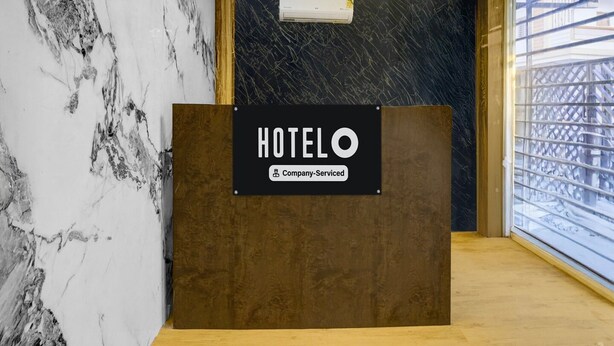A hotel reception desk with a marble wall, a chandelier, and a window with a view. - Deluxe Nagpur Royal (Nagpur)