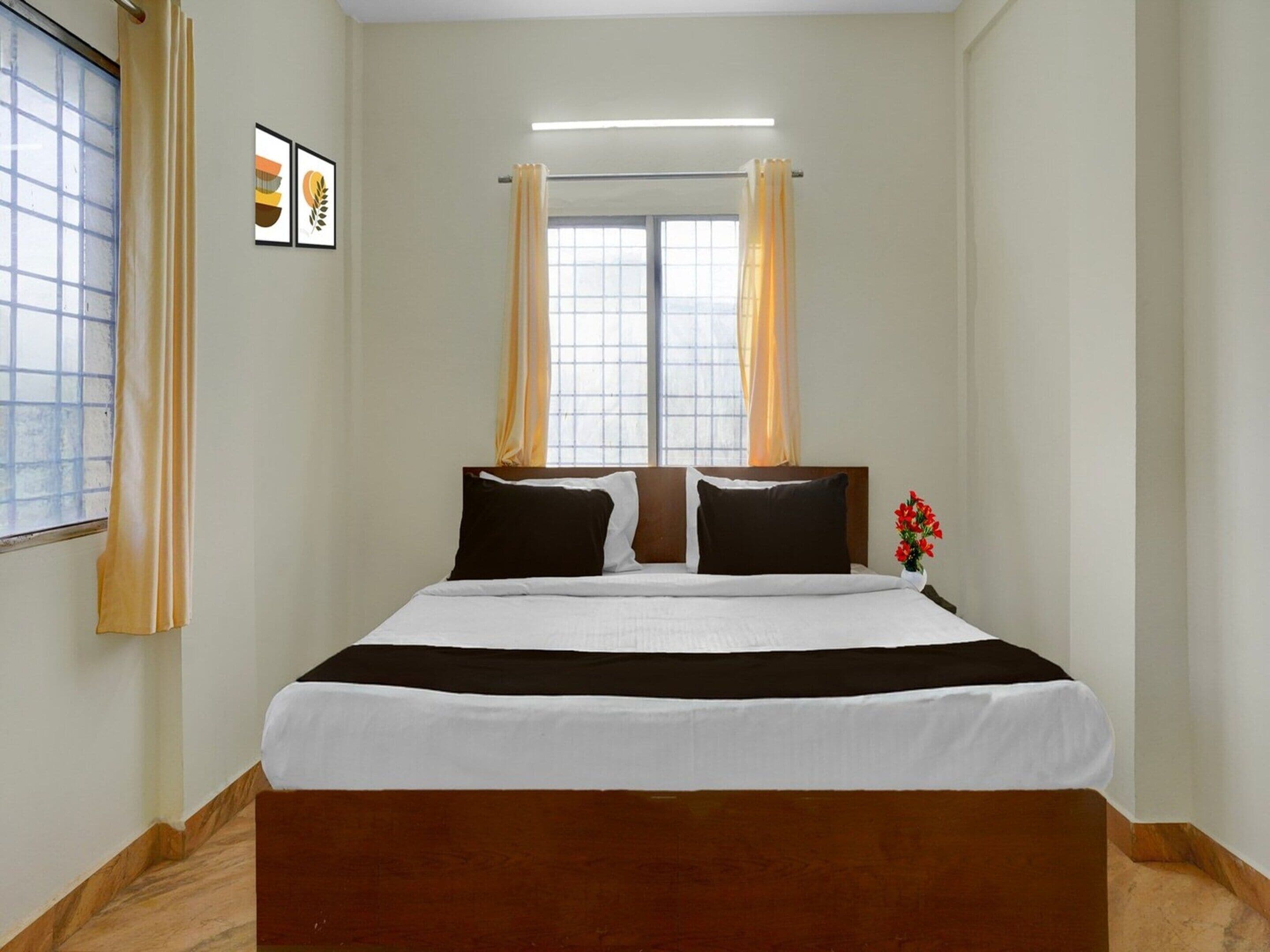 Habitación de hotel con cama, cortinas, ventana y un cuadro en la pared.