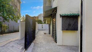 A narrow alleyway with a tiled floor, a metal gate, and a building with a green awning. - Deluxe Nagpur Royal (Nagpur)
