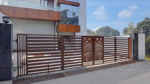 A gated entrance with a modern design, a garage door, and a building with a balcony. - Deluxebellandur Near Embassy Tech Village (Bakshi Ka Talab)