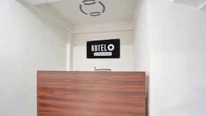 A reception desk with a sign reading 'HOTELO Company Serviced.' - Deluxebellandur Near Embassy Tech Village (Bakshi Ka Talab)