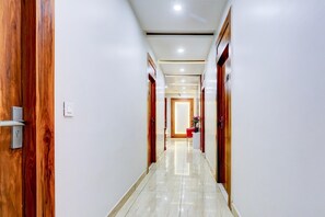 Un couloir avec des portes en bois, un sol carrelé et un éclairage encastré.