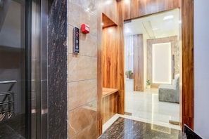 Un moderno vestíbulo de hotel con un mostrador de recepción de mármol, detalles de madera y una vista despejada hacia el interior.