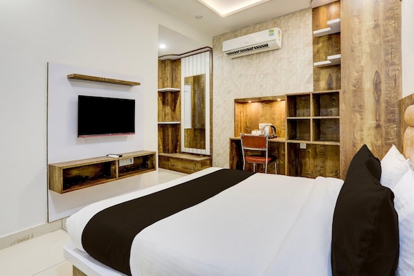 A modern hotel room with a large bed, a TV mounted on the wall, a desk with a chair, and built-in shelves. - Classic With Balcony Model Town Rohtak (Rohtak)