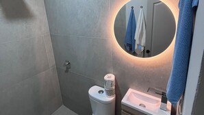 A modern bathroom with a toilet, sink, and shower.