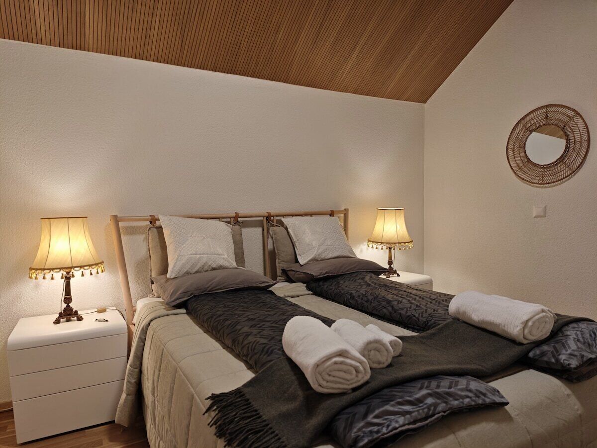 Ein Doppelbett mit zwei Nachttischen, jeweils mit einer Lampe, in einem Zimmer mit Holzboden und einer runden Wanddekoration.