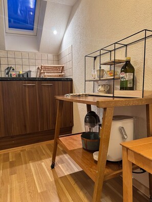Eine Küche mit Holzausstattung, einer Arbeitsplatte, einer eingebauten Ablage, einer Kaffeemaschine und einem Kühlschrank.