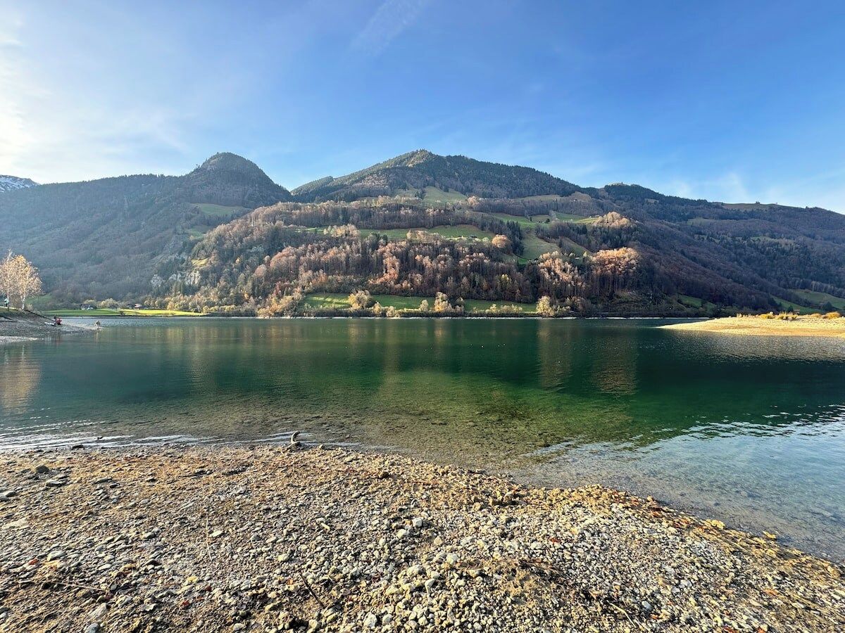 A river with a pebbly shore and a mountain in the background.