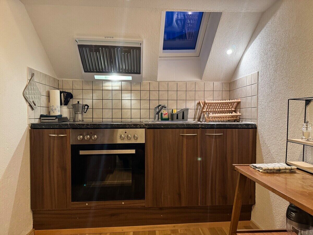 A kitchen with a built-in oven, a window above the sink, and a skylight.